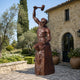 Monumental Classical Blacksmith Bronze Sculpture, 240cm, muscular male figure raising a mallet on a rocky base, outside a stone villa courtyard.