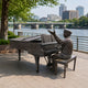 Large Traditional Pianist Bronze Sculpture, 180cm, seated bronze figure at a grand piano with hand raised, displayed outdoors along a riverside promenade with city skyline behind.