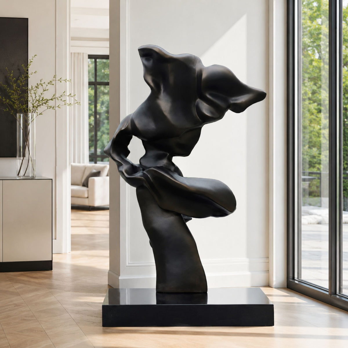 Black Abstract Female Figure on Black Base metal sculpture, 139cm, shown on a black marble base in a bright hallway near a sofa and windows.