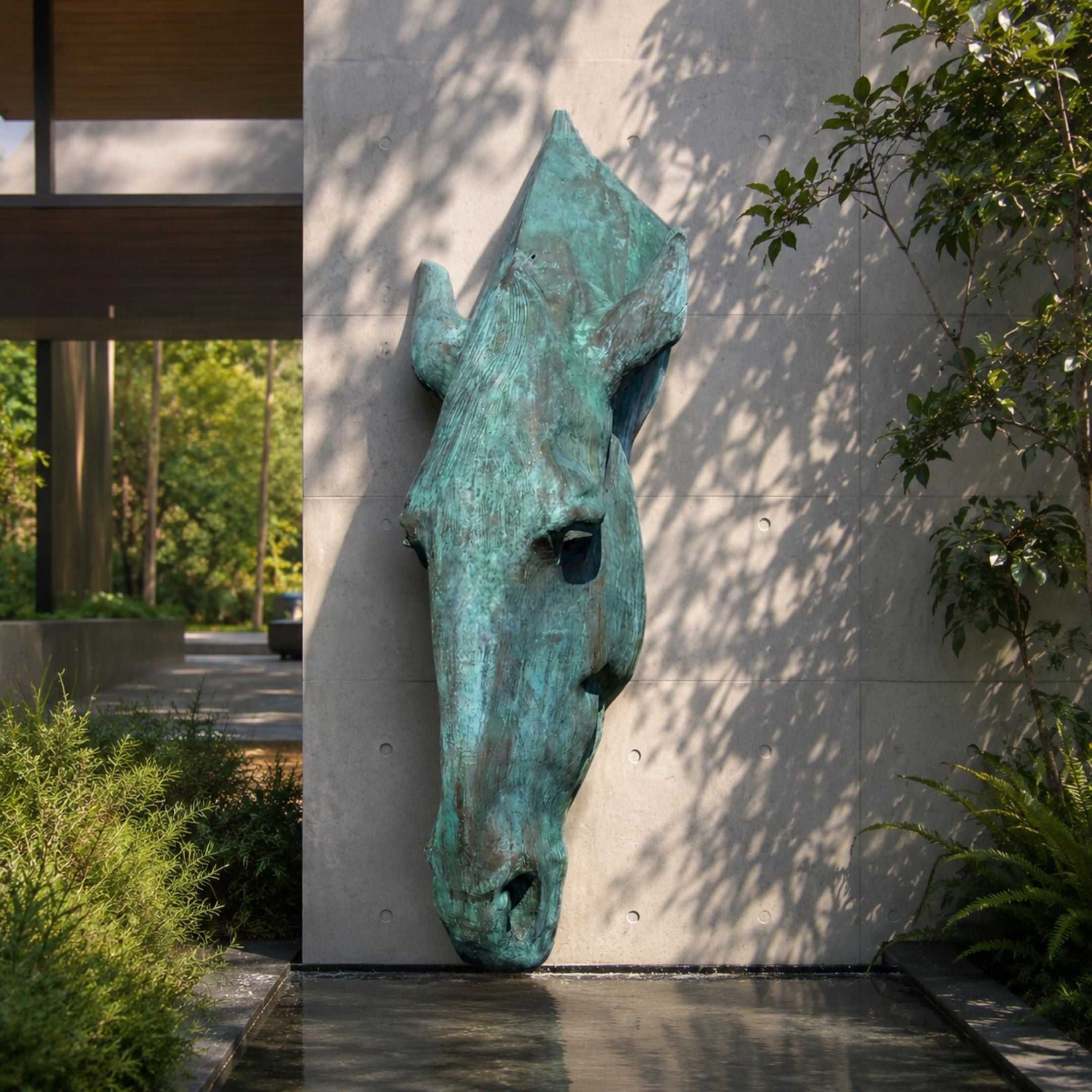 Monumental Contemporary Abstract Horse Head Bronze Sculpture in verdigris-patinated bronze, wall-mounted on a concrete facade beside greenery and a reflecting pool.