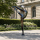 Life-Size Classical Female Ballet Dancer Bronze Sculpture, 200cm, in full arabesque penché on a stone base, set outdoors near hedges and a stone building.