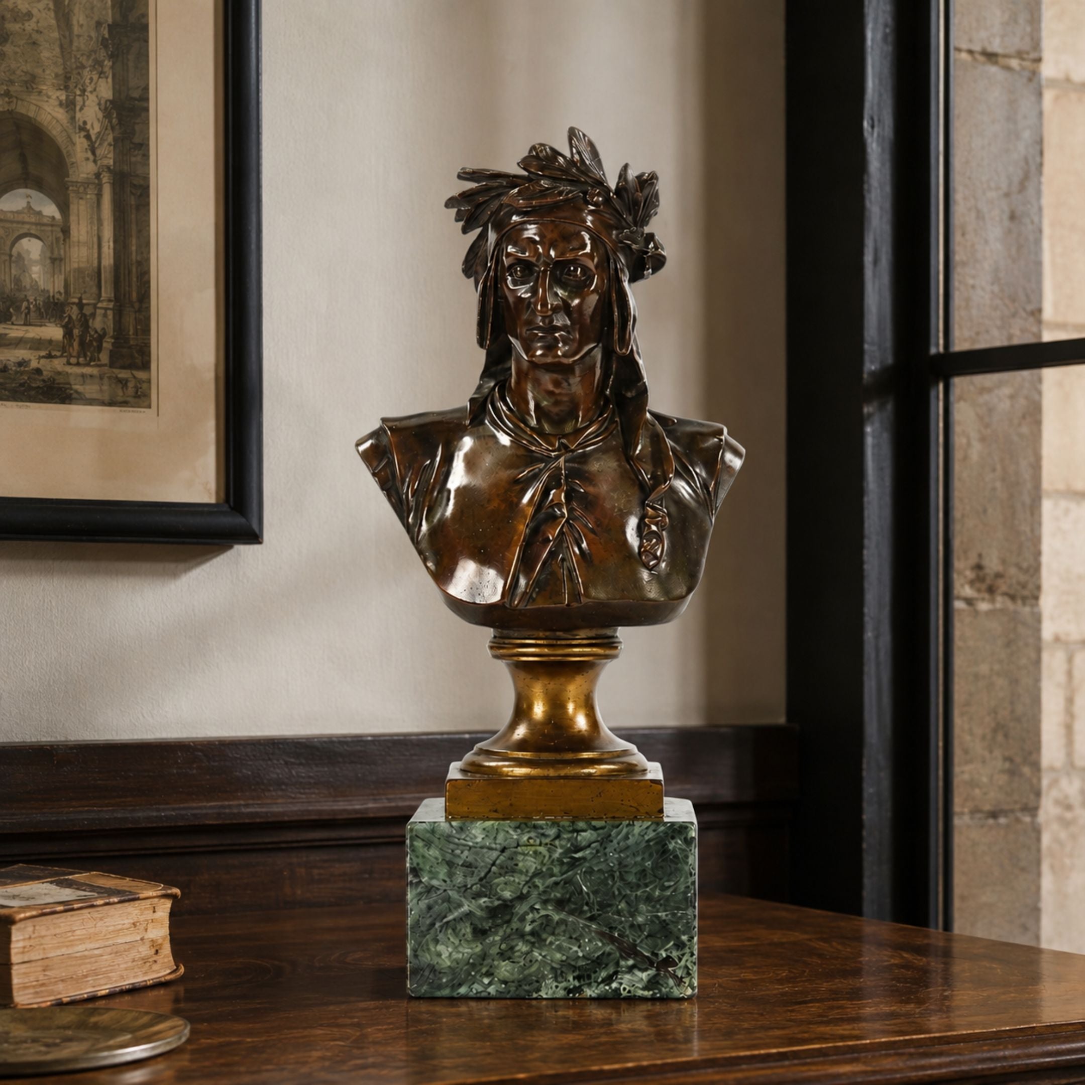 Classical Laureate Male Bust bronze sculpture with feathered headdress and draped robe, mounted on a brass and green marble base, displayed on a wooden table indoors.