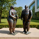 Monumental Contemporary Voluminous Nude Couple Bronze Sculpture, 300cm, facing figures on square bases outdoors on a paved terrace with lawn and trees behind.