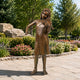Life-Size Traditional Girl Playing Violin Bronze Sculpture, 180cm, barefoot figure in a garden setting on a stone patio surrounded by flower beds and trees.
