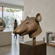 Contemporary Rat Head Bronze Sculpture, 45cm, displayed on a bronze pedestal in a gallery interior with bookshelf and view to an outdoor garden.