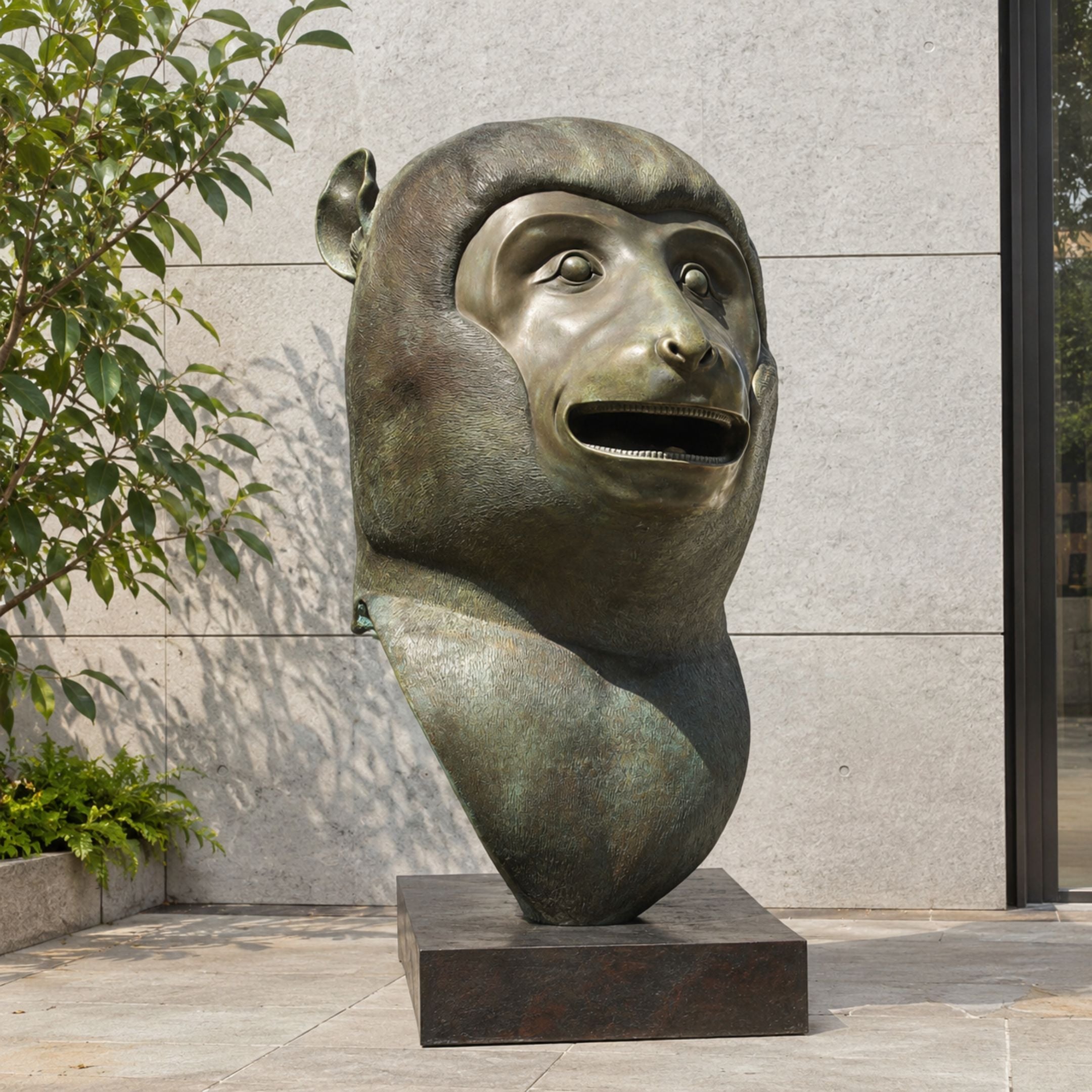 Monumental Contemporary Monkey Head Bronze Sculpture, 180cm, oversized bronze primate head with open mouth on a dark base, outdoors against a stone wall.