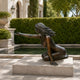 Life-Size Classical Seated Woman Bronze Sculpture, 150cm, kneeling nude figure with windswept hair and extended arm, on a stone plinth beside an outdoor pool.