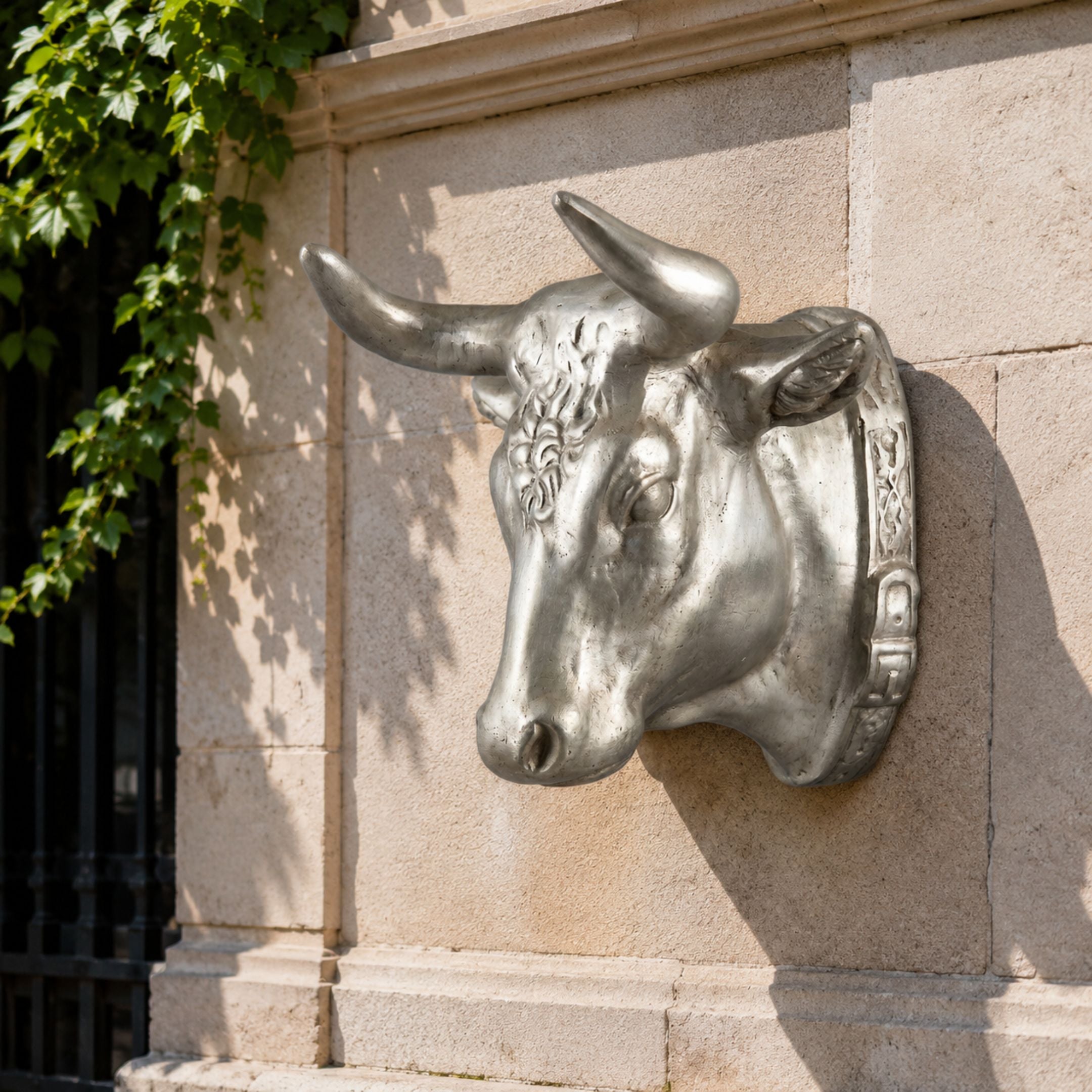 Classical Bull Head Bronze Relief - 70cm in silver-toned metal, mounted on a stone wall with curved horns and collar detail, ivy visible nearby.