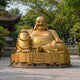 Monumental Traditional Seated Budai Bronze Sculpture, 220cm, gold-toned laughing Buddha holding prayer beads on a stone base outdoors near a pavilion.