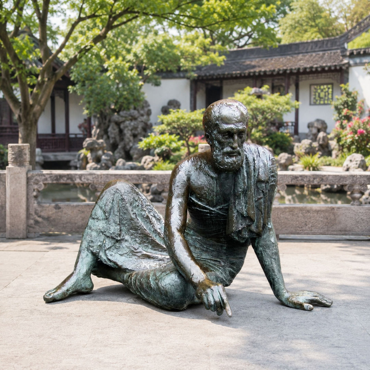 Life-Size Classical Reclining Bearded Scholar Bronze Sculpture, 120cm, in antique patina finish, seated on a garden courtyard patio near a stone balustrade.