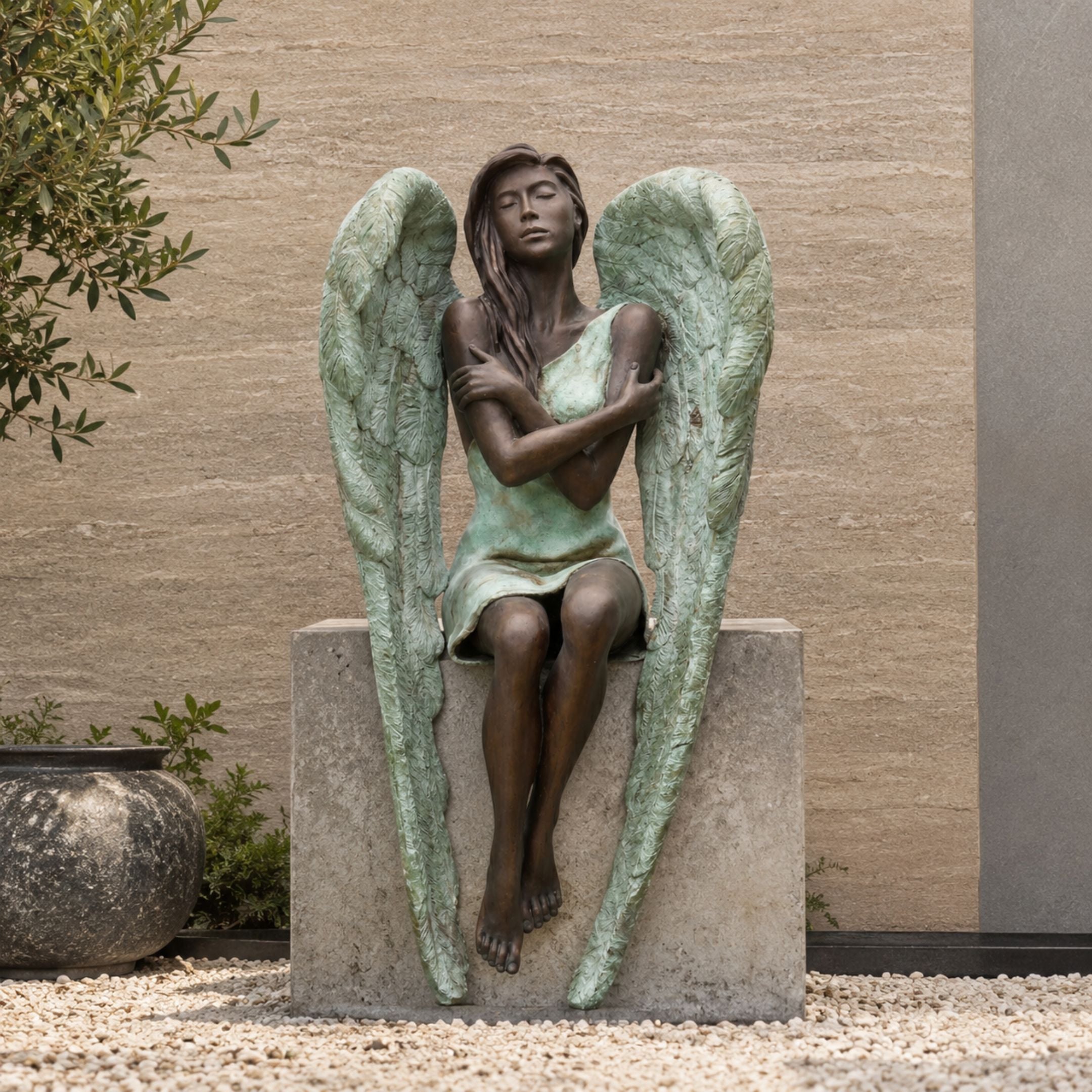 Large Classical Seated Angel Bronze Sculpture, 180cm, shown seated on a stone base with arms crossed and large feathered wings in bronze and green patina, set outdoors against a stone wall.