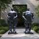 Monumental Contemporary Voluminous Standing Figures Bronze Sculpture, 350cm, mirror-polished black bronze male and female figures on square bases outside a glass entrance.