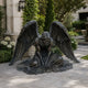 Large Classical Kneeling Angel Bronze Sculpture, 200cm, dark patina finish, wings spread wide, head bowed, set on a garden patio near greenery.