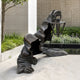 Contemporary Hooded Phantom Figure Bronze Sculpture, 150cm, shown in a courtyard, cloaked figure crawling low with arm raised holding a lantern by its chain.
