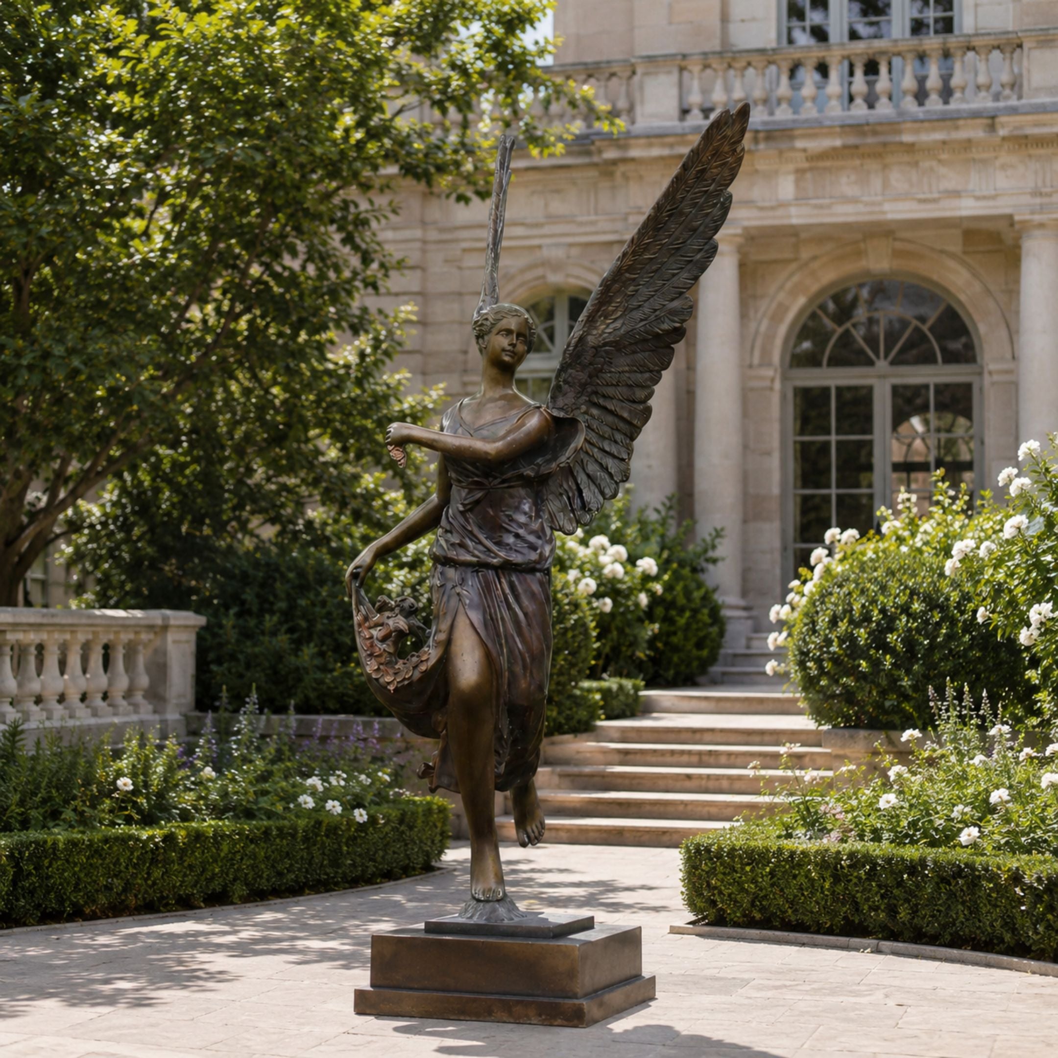 Monumental Classical Angel with Flower Basket Bronze Sculpture, 240cm, on a stone base in a garden courtyard near a stone mansion.