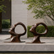 Large Contemporary Abstract Face Bronze Sculpture, 150cm, pair of tilted heads with circular voids, on flagstone terrace near hedges and trees.