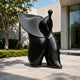 Monumental Contemporary Abstract Female Figure Bronze Sculpture, 220cm, black finish with wide sweeping upper form, displayed on a patio near a modern building.