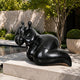 Large Contemporary Abstract Reclining Figure Bronze Sculpture, 120cm, in black cast bronze on a stone plinth beside a garden pool and potted greenery.