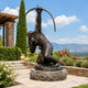 Life-Size Contemporary Kneeling Archer Bronze Sculpture, 260cm, on a stone base in a patio setting with mountain views and greenery.