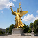 Monumental Classical Winged Victory Goddess Bronze Sculpture, 280cm, gold gilt Nike with spread wings, laurel wreath and sceptre, on a stone pedestal outdoors.