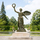 Life-Size Classical Winged Angel Bronze Sculpture, 240cm, cast bronze figure raising a laurel wreath with wings spread, set on a stone plinth in a garden.
