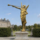 Monumental Classical Herald Angel Bronze Sculpture, 280cm, gilt gold finish with spread wings and raised trumpet, on a stone plinth in a garden setting near a manor house.