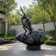 Monumental Contemporary Contemplative Hare Bronze Sculpture, 340cm, black bronze hare seated on a textured boulder in a courtyard garden setting.