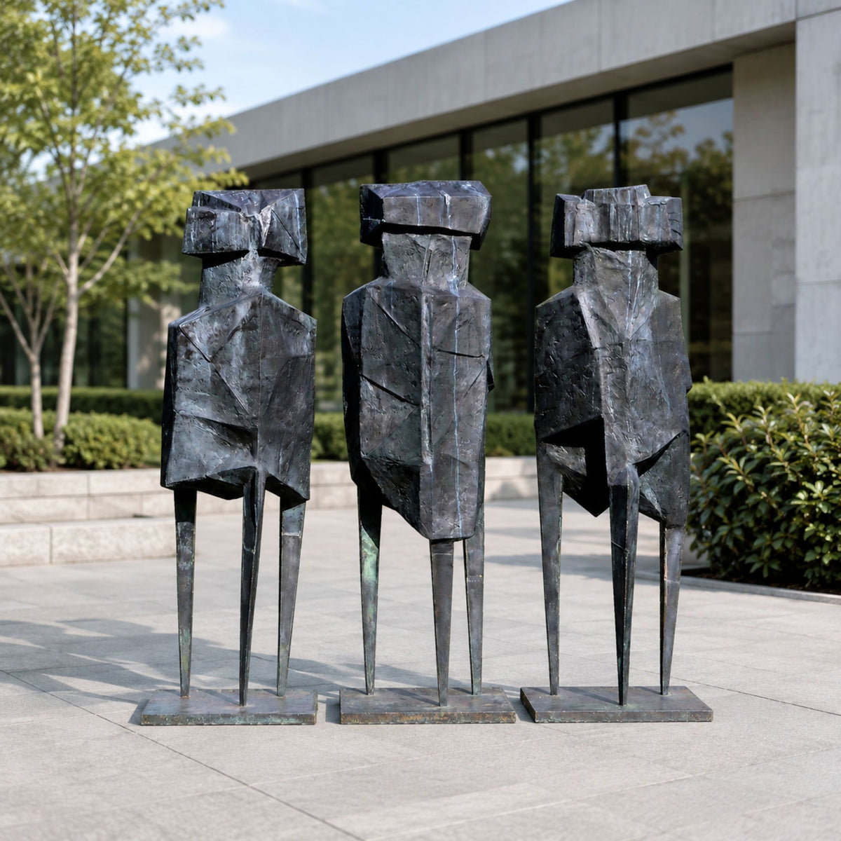 Monumental Modern Trio of Abstract Geometric Figures Bronze Sculpture, 250cm, three faceted figures on tall stilted legs outside a glass building.