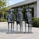 Monumental Modern Trio of Abstract Geometric Figures Bronze Sculpture, 250cm, three faceted figures on tall stilted legs outside a glass building.