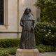 Life-Size Traditional Standing Nun Bronze Statue, 250cm, dark patina figure in habit and veil holding a book and rosary, on a stone base outdoors near greenery.