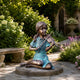 Life-Size Traditional Girl Playing Violin Bronze Sculpture by Giant Sculptures with two-tone brown and turquoise patina, displayed on a stone garden path beside a bench.