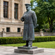 Life-Size Traditional Standing Military Figure Bronze Sculpture, 220cm, on a stone base outdoors near hedges and a stone building facade.