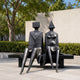 Monumental Modern Abstract Seated Figures Bronze Sculpture, 220cm, black cast bronze pair with cubic and conical heads on a bench, outdoor courtyard setting.