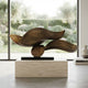 Bronze Abstract Organic Wave Sculpture Brass, 91cm, on a black base atop a travertine plinth in a bright room overlooking a garden.