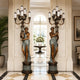 Large Classical Candelabra Torchiere Figure Bronze Sculpture, 220cm pair of draped female figures holding nine-arm candelabra, flanking an arched hallway entrance.