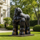 Monumental Contemporary Rotund Horse Bronze Sculpture, 300cm, on a plinth in a landscaped garden beside a stone building, dark bronze finish with rounded, oversized form.