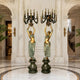 Pair of Large Classical Draped Goddess Candelabra Bronze Sculptures, 220cm, gold and green patina figures raising nine-arm candelabra in a marble entry hall.