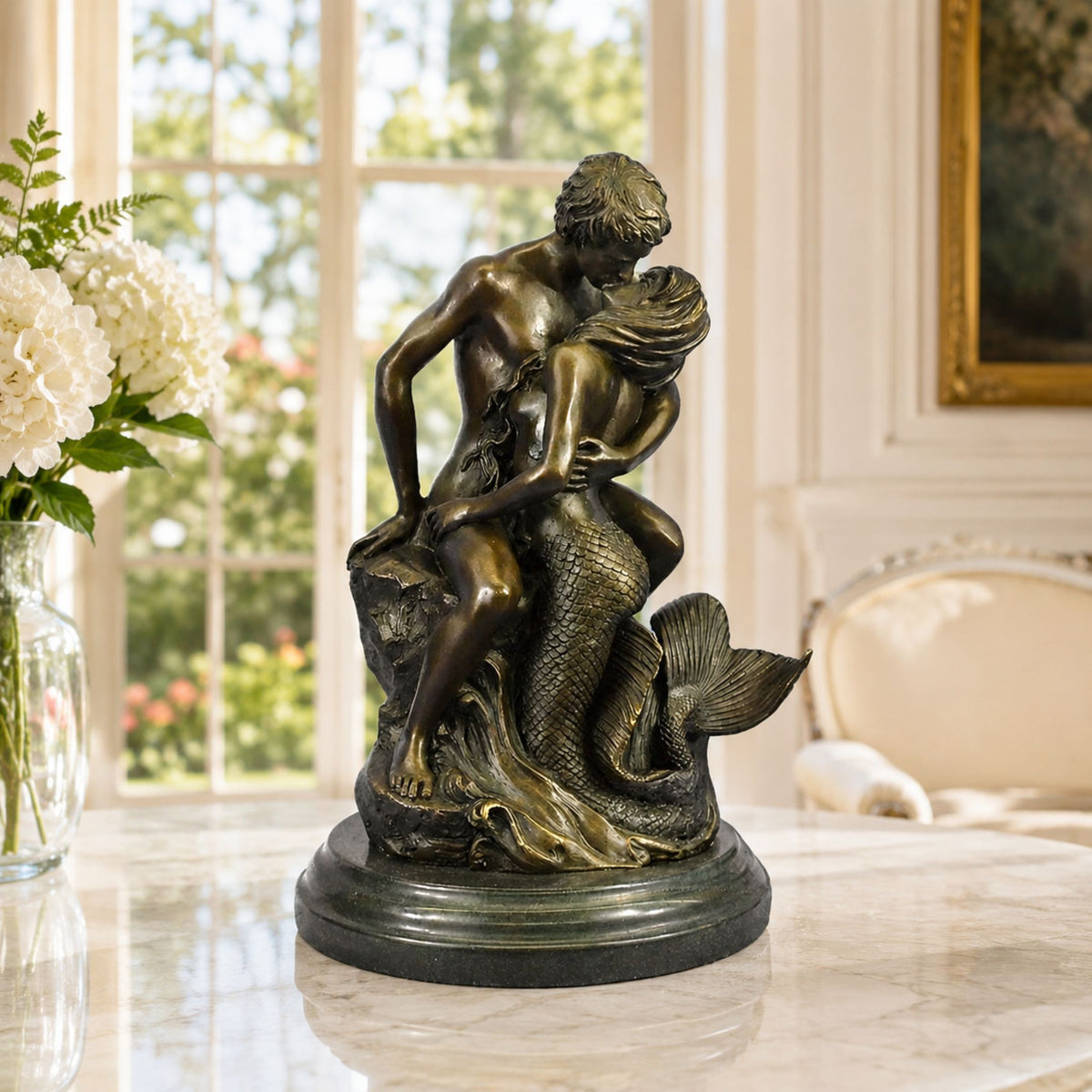 Classical Male Figure and Mermaid Bronze Sculpture, 45cm, on a marble base, shown on a marble table in a bright room with white flowers nearby.
