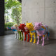Row of Contemporary Life-Size Painted Cow Bronze Sculptures by Giant Sculptures in pink, yellow, red, green and blue high-gloss finishes in a concrete entryway.