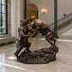 Monumental Bull and Bear Combat Bronze Sculpture by Giant Sculptures displayed in a marble lobby, showing both animals rearing on a rocky base marked STIFEL.