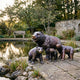 Large Traditional Bear Family Bronze Sculpture by Giant Sculptures, adult bear with open mouth and three cubs on stone paving beside a garden pond.