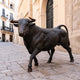 Life-Size Walking Longhorn Bull Bronze Sculpture by Giant Sculptures in dark patina, positioned mid-stride on stone paving beside an arched palazzo entrance.