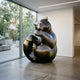 Large Contemporary Seated Bear Bronze Sculpture by Giant Sculptures in a dark patina with golden highlights, displayed in a gallery interior beside floor-to-ceiling windows.