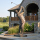 Monumental Contemporary Golfer Bronze Sculpture by Giant Sculptures at 310cm, shown mid follow-through outside a stone clubhouse with a golf course beyond.