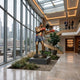 Life-Size Contemporary Male Boxer Bronze Sculpture by Giant Sculptures with red gloves and blue shorts, displayed in a sunlit atrium lobby beside a spiral staircase.