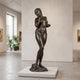 Large Classical Standing Nude Female Figure Bronze Sculpture by Giant Sculptures with dark patina, displayed on a low white plinth in a gallery interior.