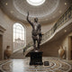 Monumental Classical Roman Warrior Bronze Statue 400cm by Giant Sculptures, arm raised, on a black plinth in a domed rotunda with a spiral staircase.