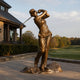 Life-Size Contemporary Female Golfer Bronze Sculpture by Giant Sculptures shown at full follow-through swing on a paved terrace beside a clubhouse and golf course.