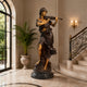 Life-Size Classical Violinist Bronze Sculpture by Giant Sculptures displayed in a marble foyer beside an arched window, palm plant, and ornate staircase.