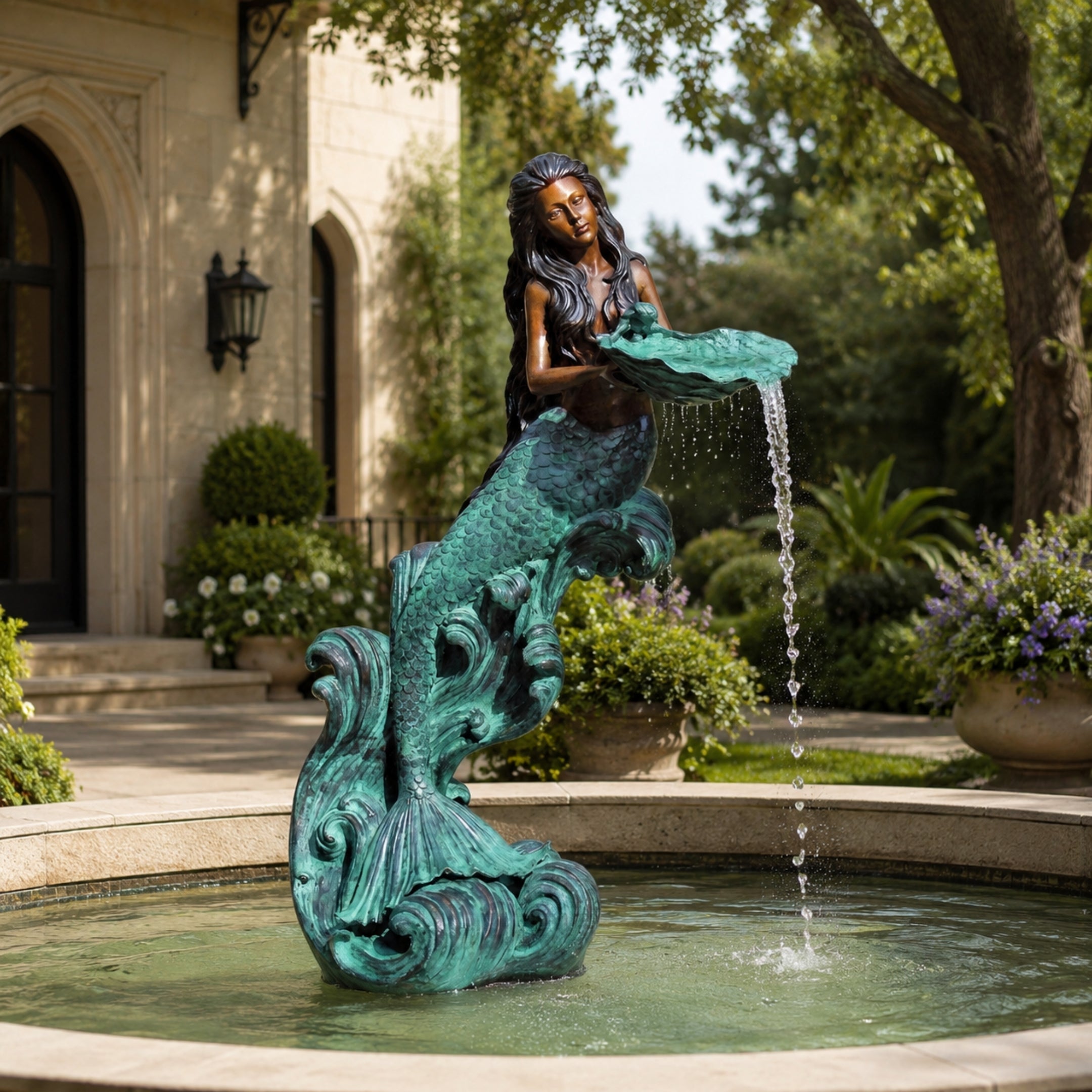 Classical Mermaid Fountain Bronze Sculpture by Giant Sculptures with dual-tone patina, pouring water from a shell dish into a garden pool by a stone manor.